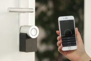 smart lock next to a hand holding a smart phone 